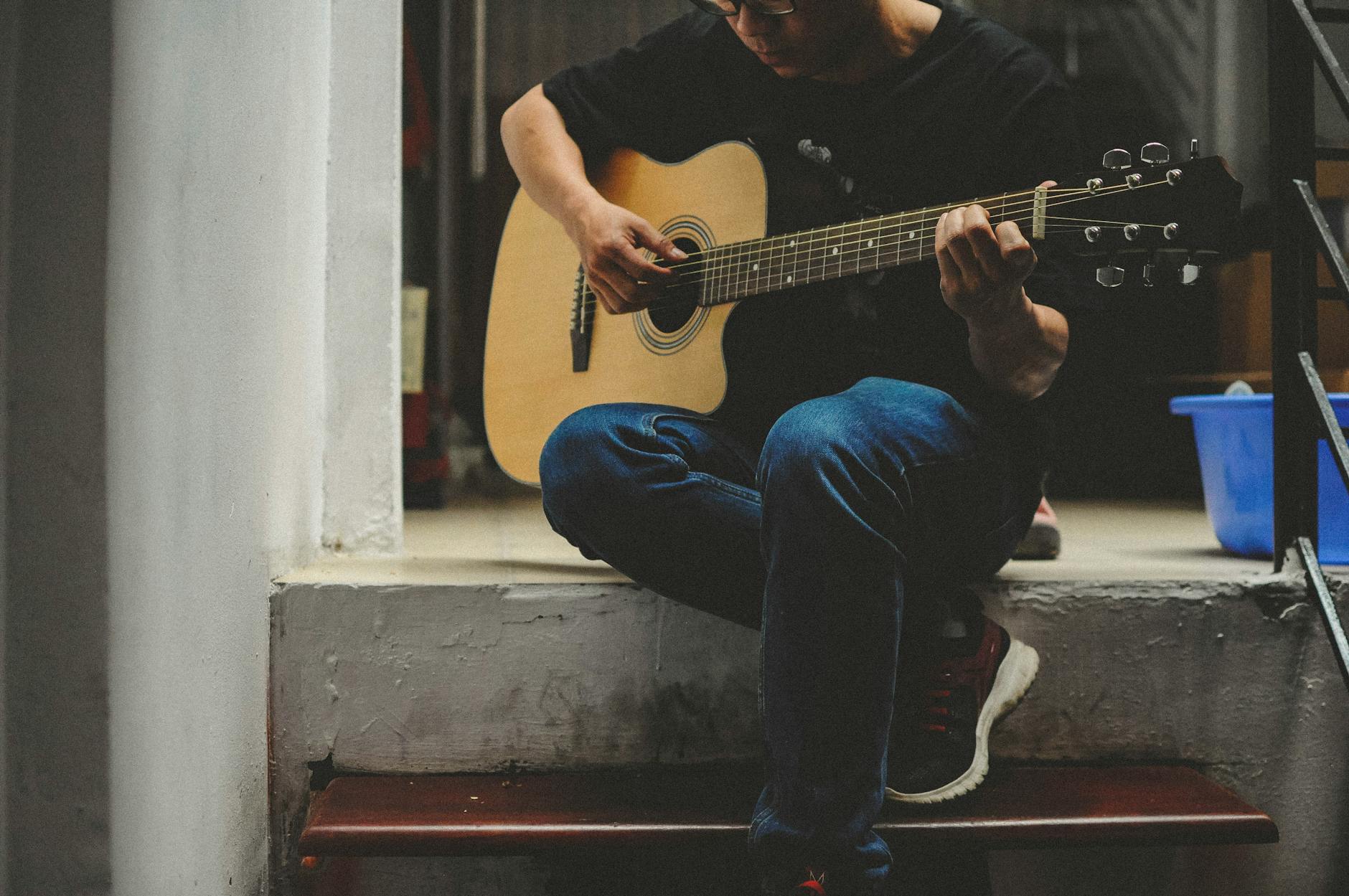 man playing acoustic guitar while sitting